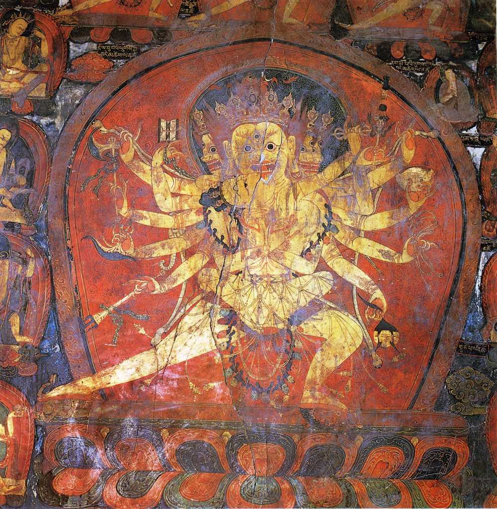 Tibet Guge 08 Tsaparang 04 Yamantaka Temple Chakrasamvara On the right wall is a four-headed, 12-armed large painting of Chakrasamvara (Tib. Demchog), embracing his consort Vajravarahi. Vajravarahi�s left hand circles Chakrasamvara�s neck while her right holds a vajra. In his right hands he holds a vajra lasso, a drum, a hatchet, a chopper and a trident; while his left hands hold the vajra lasso, a skull full of blood, a noose and the heads of Brahma. Photo - Weyer/Aschoff: Tsaparang, Tibets Grosses Geheimnis.